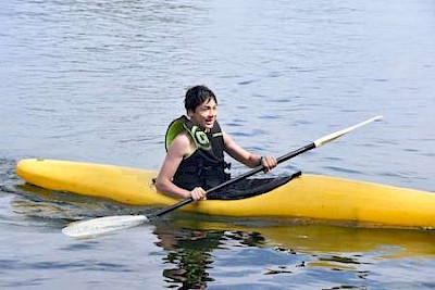 young boy riding the kayak during summer camp